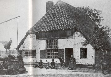<p>19e-eeuwse foto van de voorgevel van een boerderij bij Doetinchem. In de geheel in vakwerk uitgevoerde voorgevel is een ankerbalkgebint opgenomen. Onder de dakvoet is nog het onderste deel van de oorspronkelijke beplanking van de geveltop te zien. Deze geveltop is waarschijnlijk bij het verwijderen van de rieten dakbedekking en de realisatie van een wolfeind verdwenen. </p>

